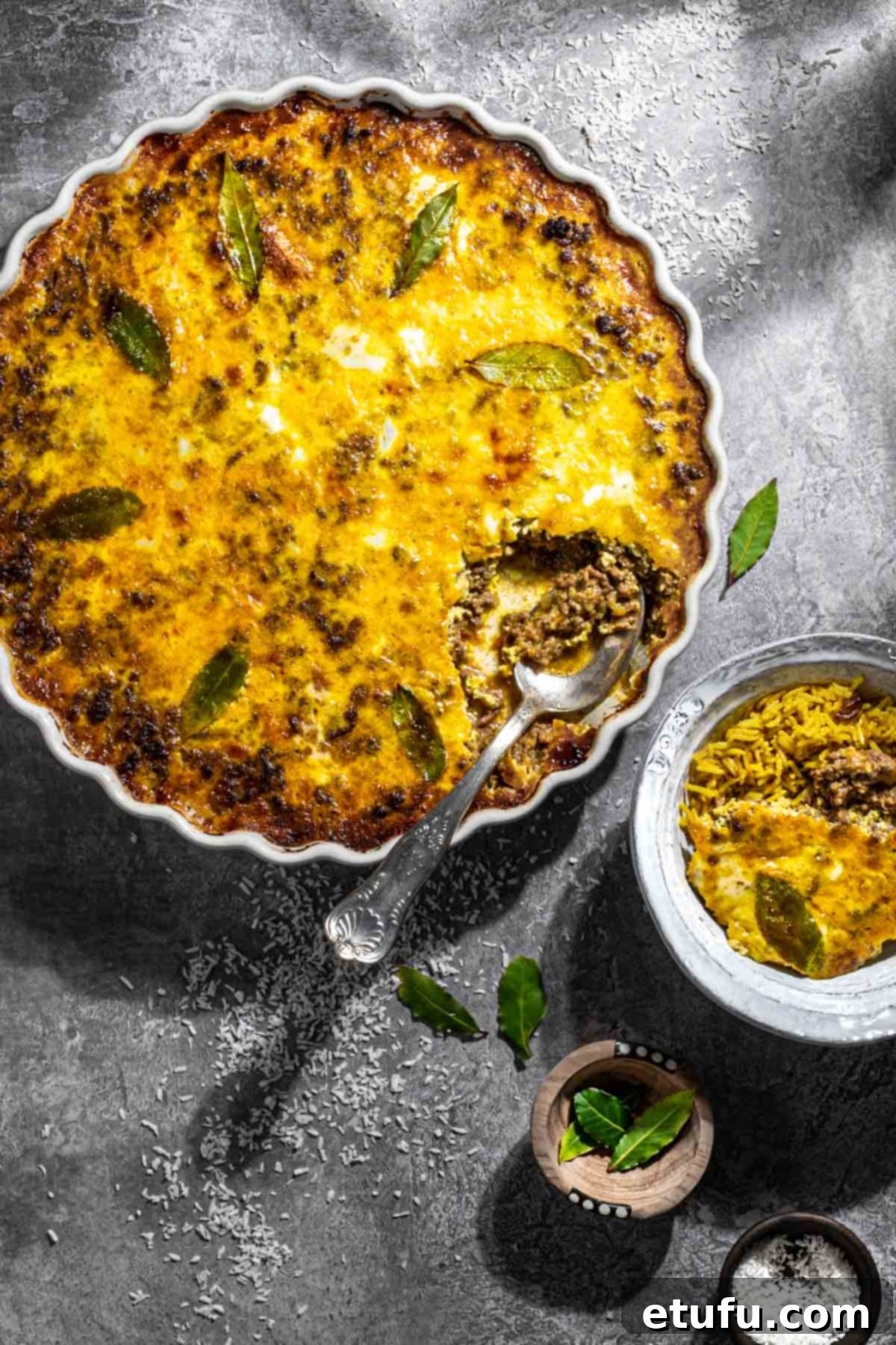 Easy South African bobotie in a white dish on a grey background, ready to be served.