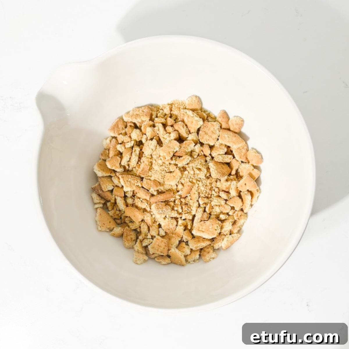 Effortless Date Bars 13 Crushed digestive biscuits with visible chunks in a large white bowl.