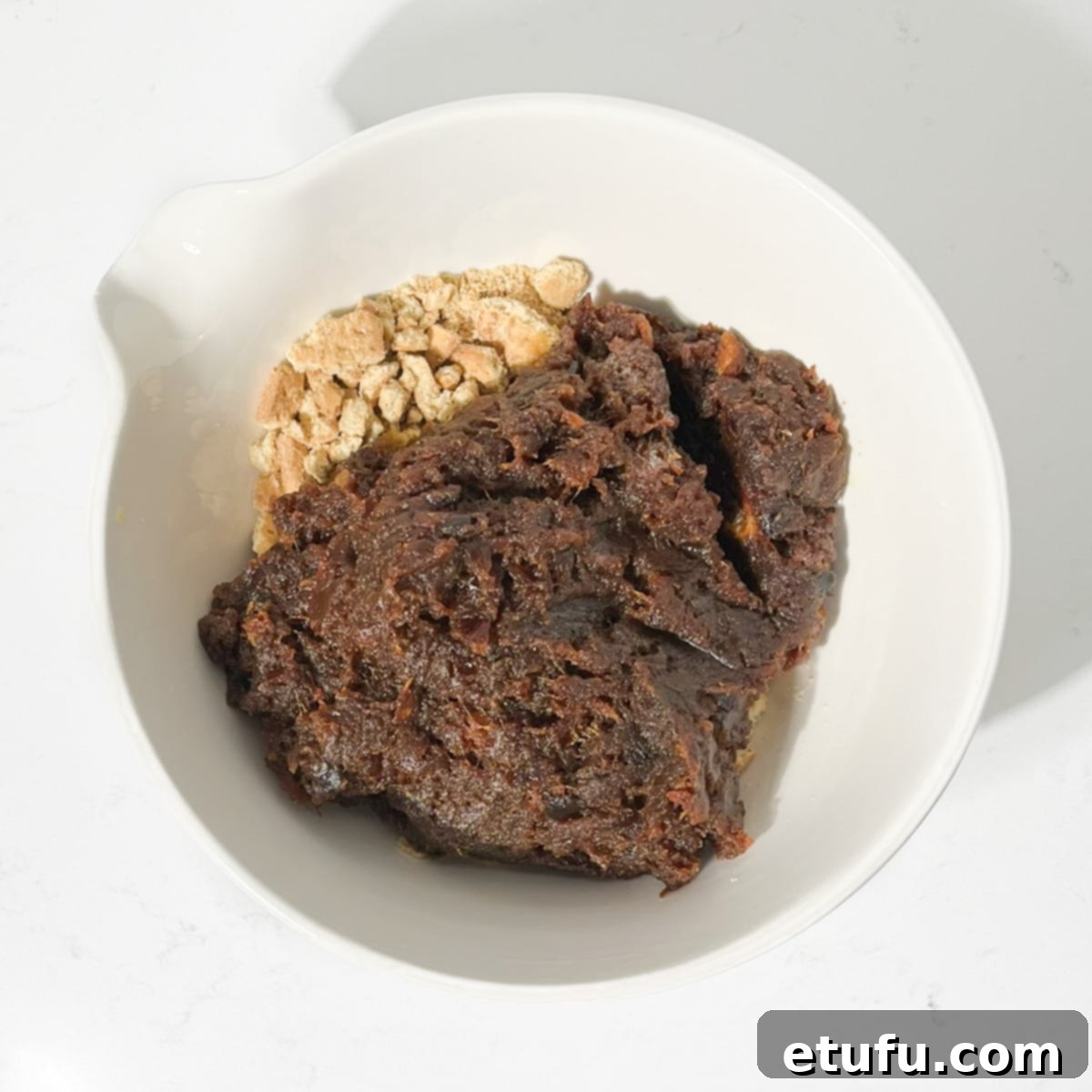 Effortless Date Bars 14 Adding the warm, cooked date mixture to the bowl of crushed biscuits.