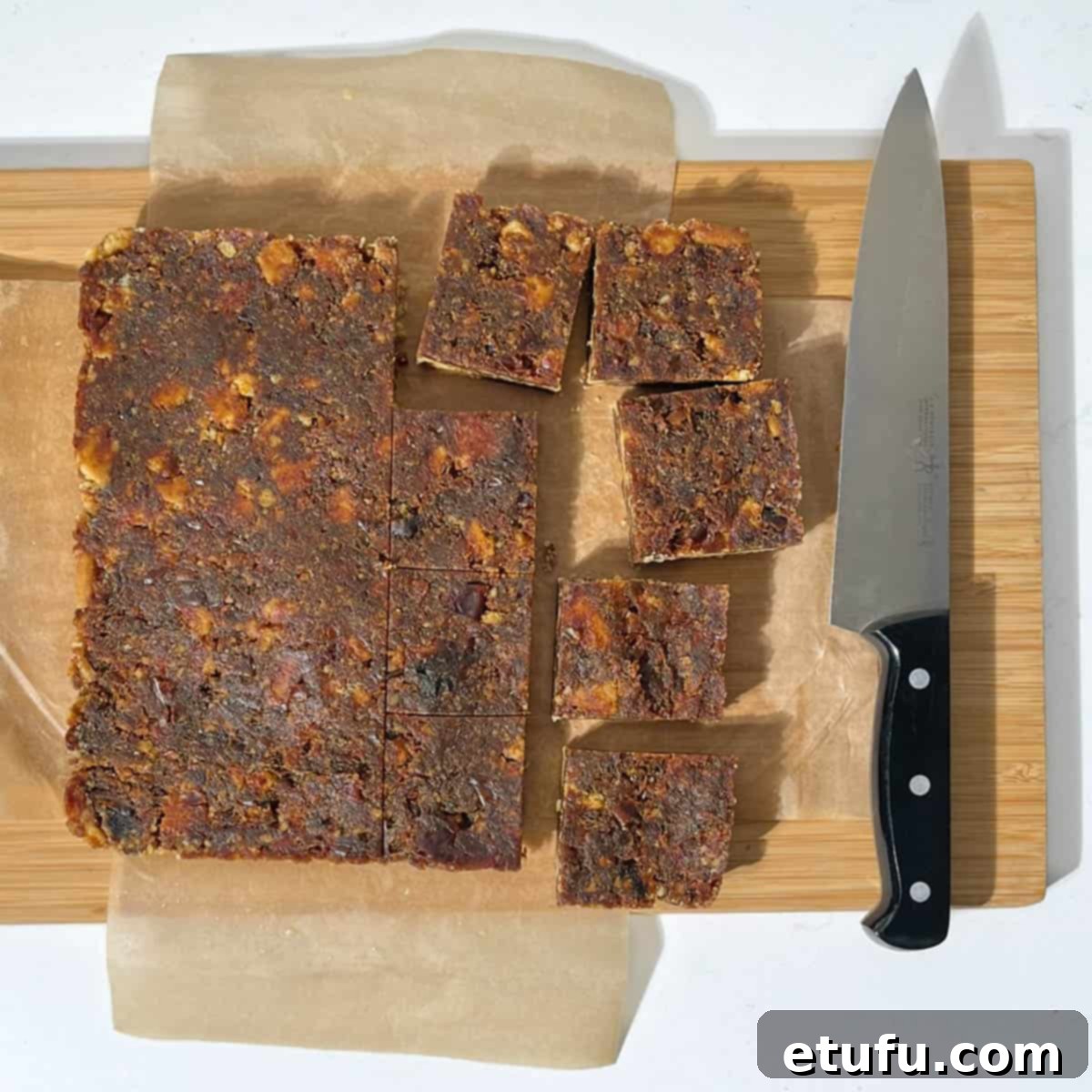 Effortless Date Bars 18 Perfectly sliced date squares arranged on a wooden chopping board.