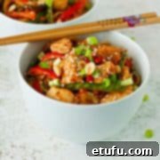 Two bowls of chicken stir fry on a white background with chopsticks