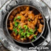 Aromatic beef curry with coconut milk in a balti bowl with a side of rice.