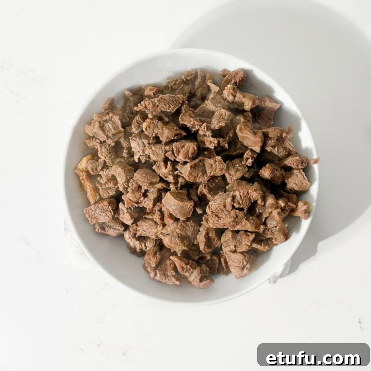 Browned meat in a white bowl.