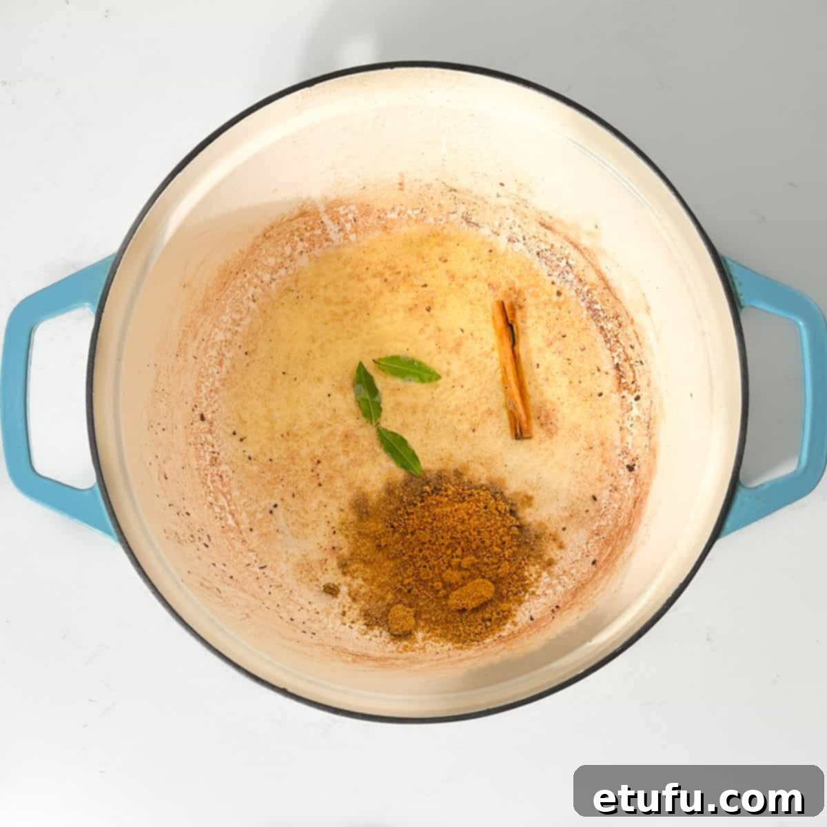 Adding the bay leaves and curry powder to the butter in a large saucepan.