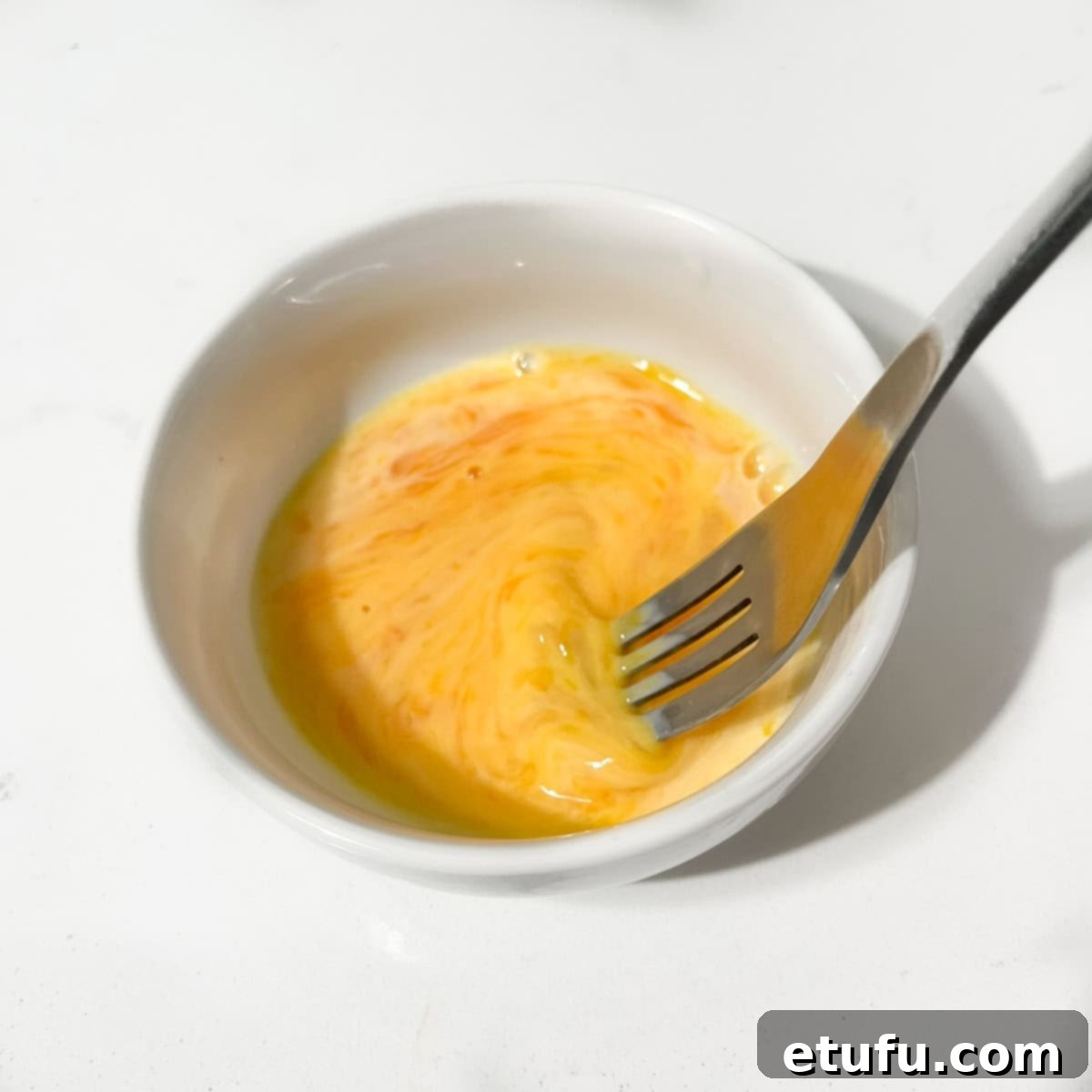 Whisking the egg wash in a small bowl.