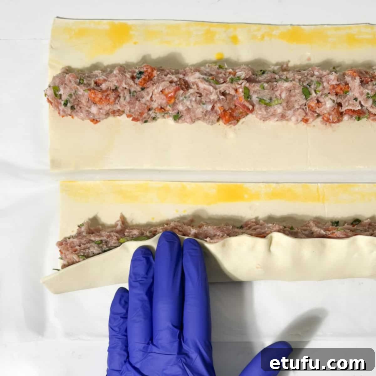 Folding the pastry over the sausage roll filling.