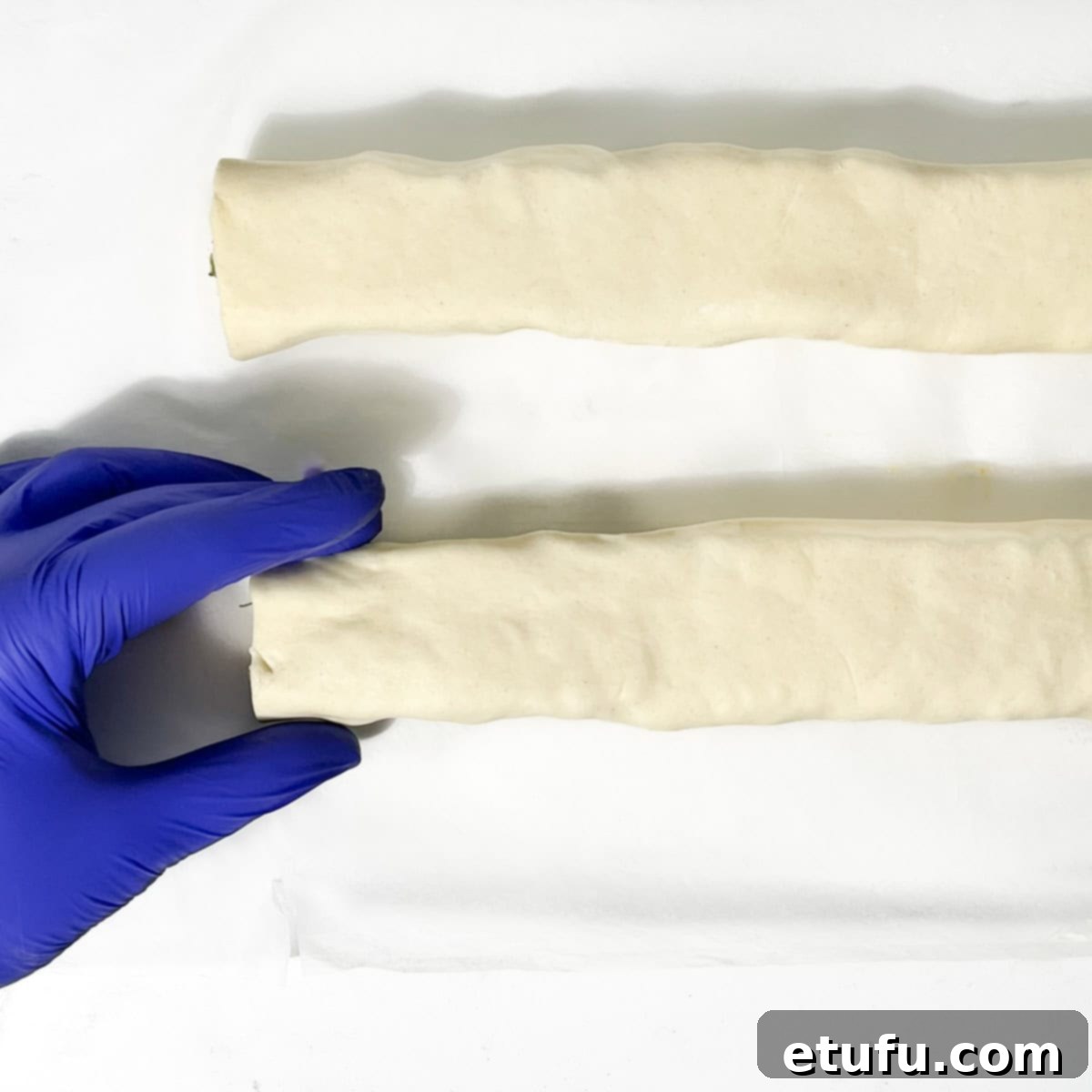 Smoothing out the sausage rolls before slicing them.