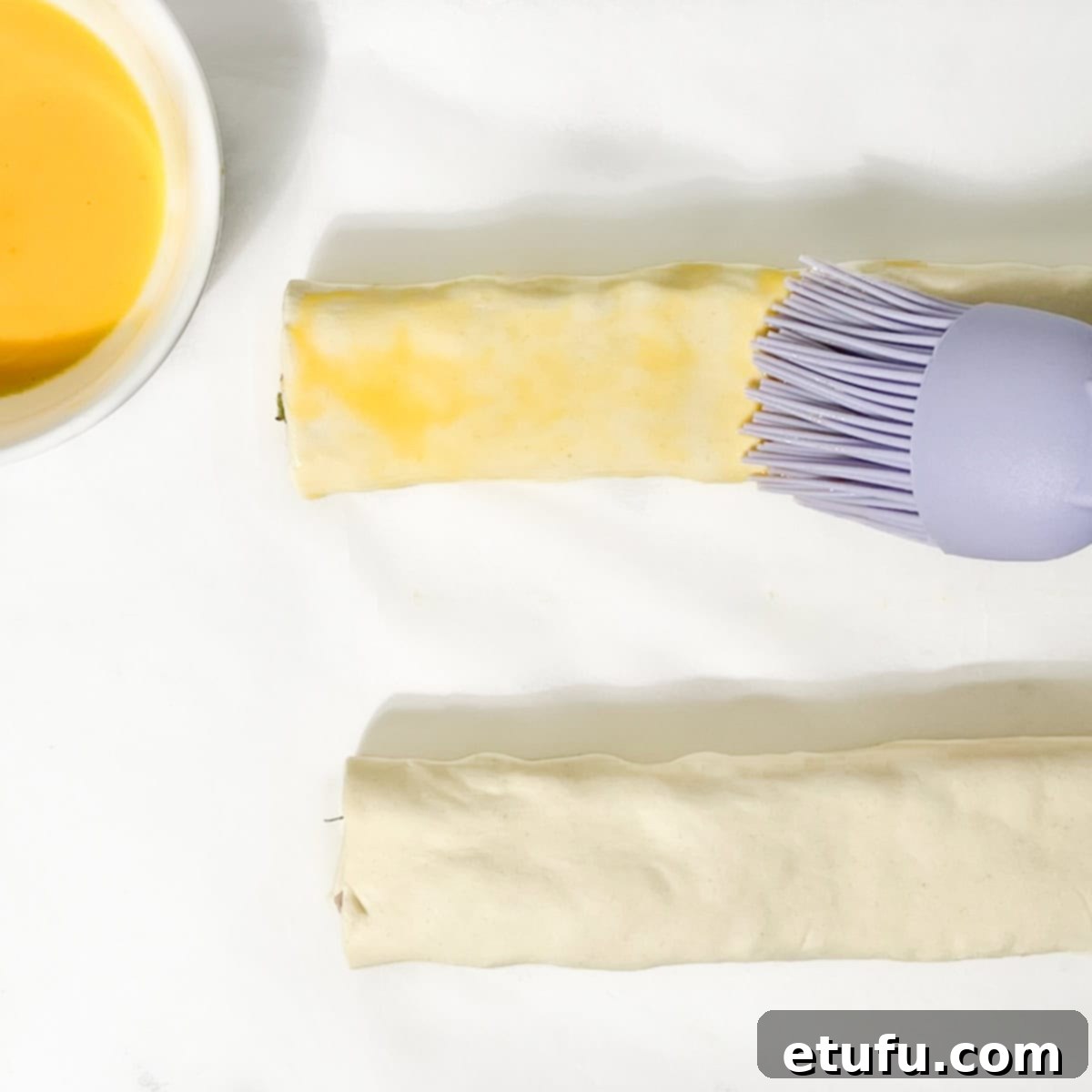Brushing egg wash onto the sausage rolls.