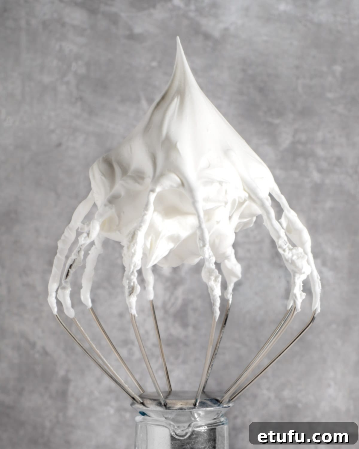Marshmallow fluff on a whisk with stiff peaks, ready to be used as a delicious dessert topping.