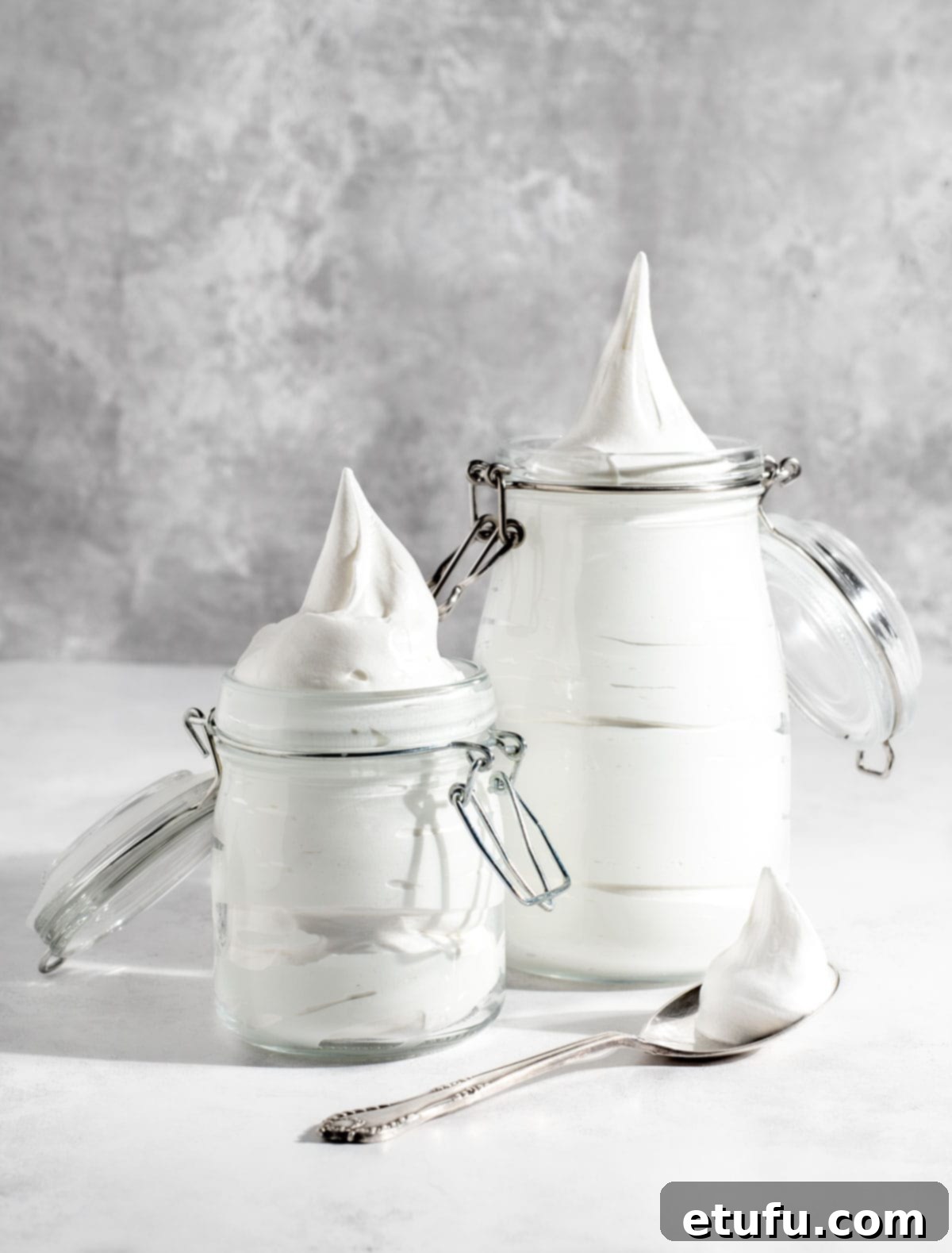 Two jars filled with freshly made homemade marshmallow fluff, showcasing its creamy texture.