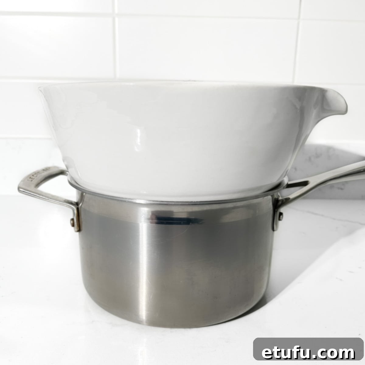 A large white heatproof bowl placed on top of a saucepan, ready for a double boiler setup.