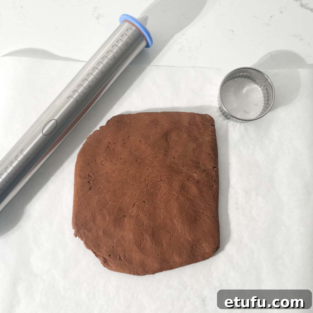 A flat disc of shortbread dough on a large piece of parchment paper.