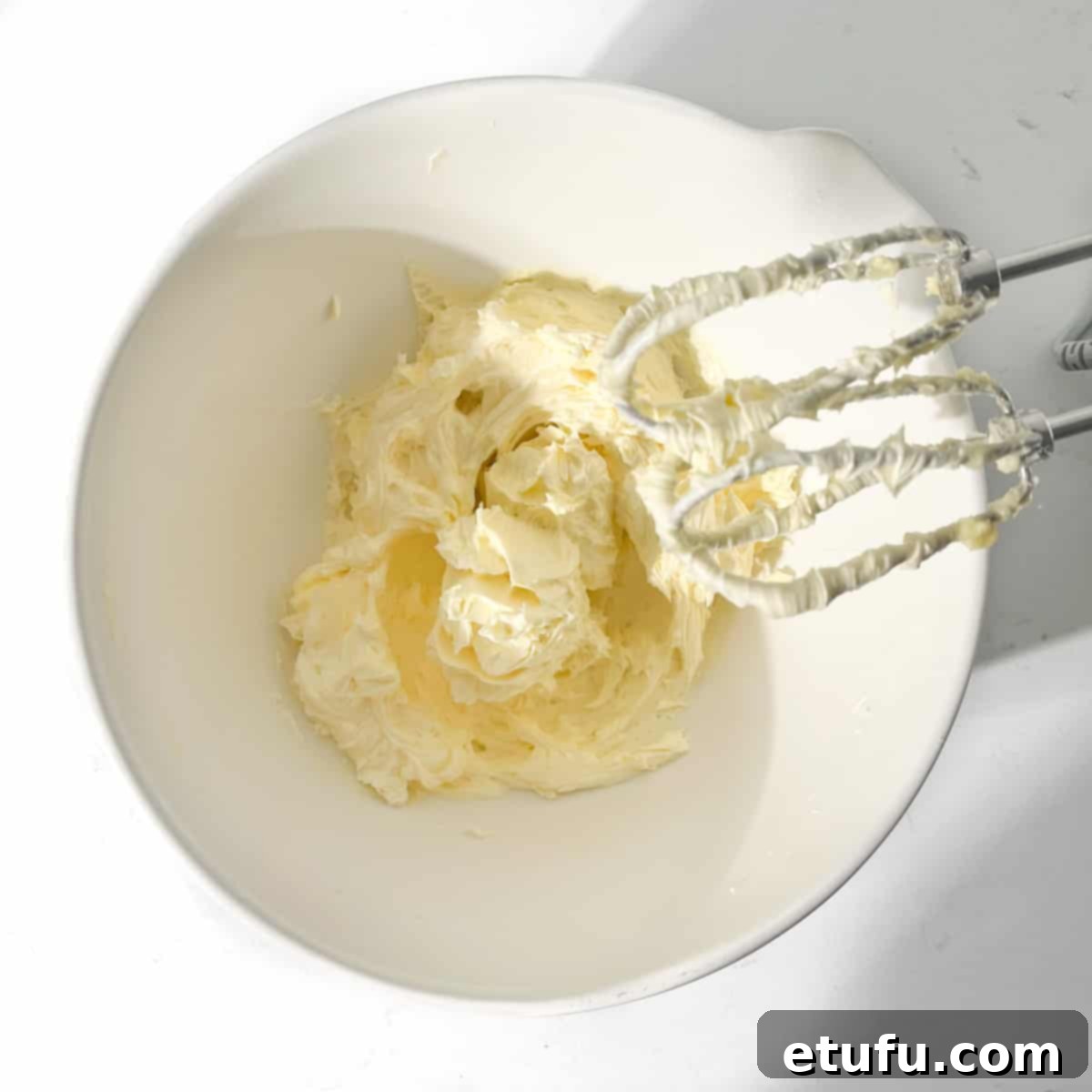 Creaming butter and sugar together in a large white bowl with an electric hand mixer.