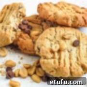 Grandma's Eggless Peanut Butter Cookies 5 A delectable pile of peanut butter chocolate chip cookies, garnished with loose peanuts and chocolate chips.