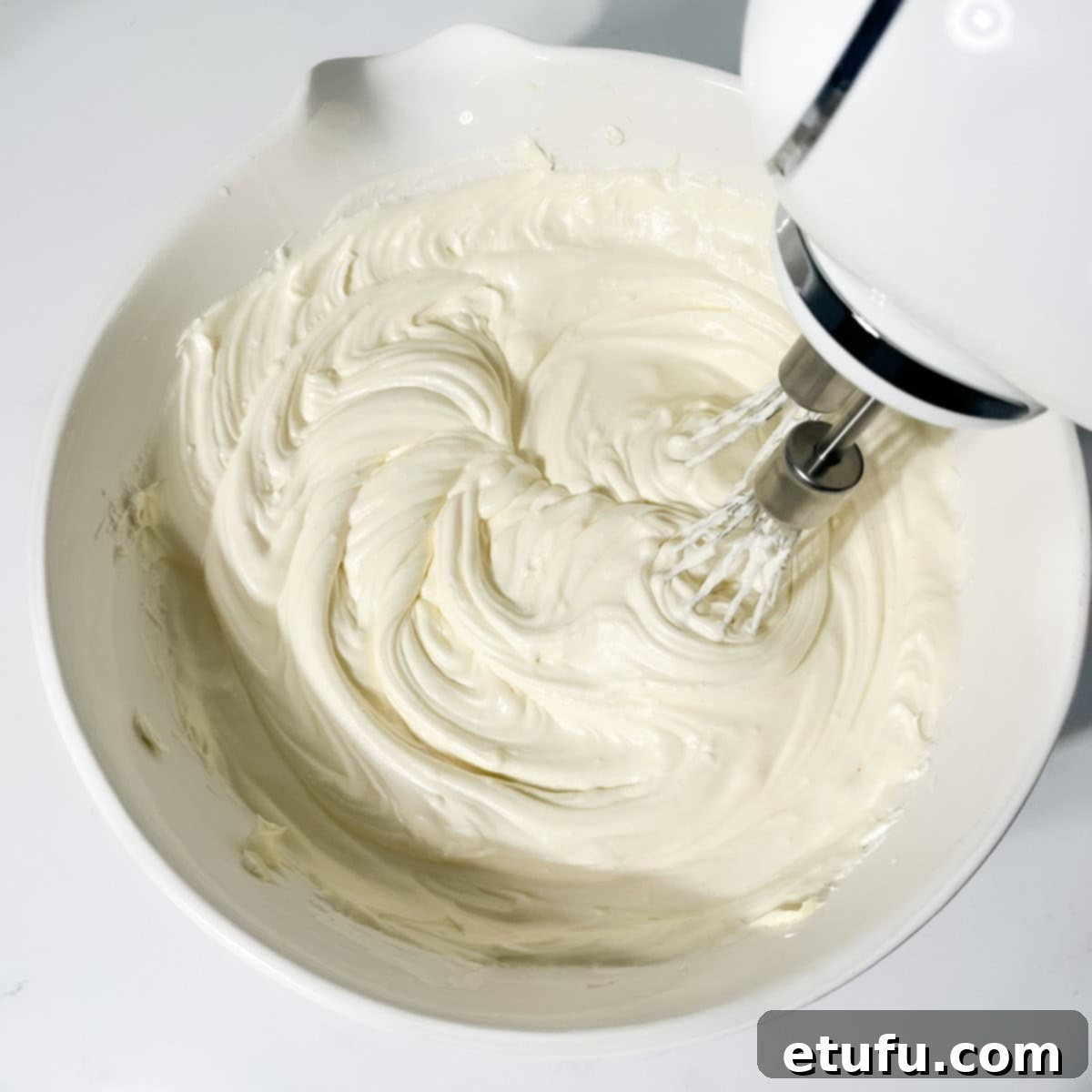 Gently whisking the white chocolate into the cheesecake mixture until silky smooth.