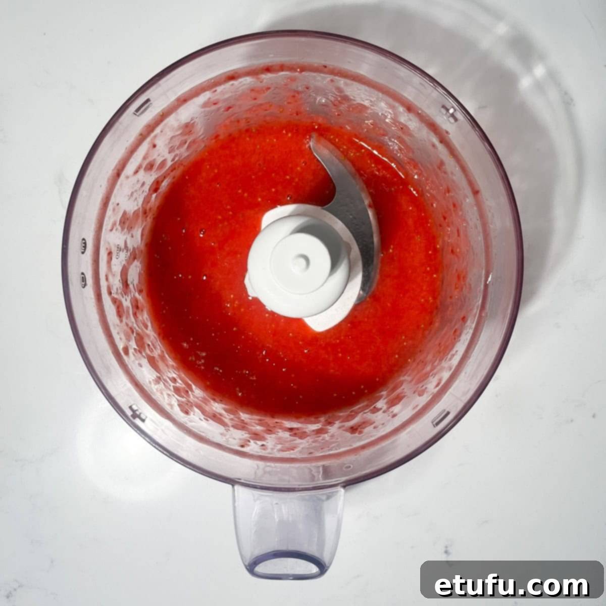 Pureed strawberries in a blender, ready for cooking.