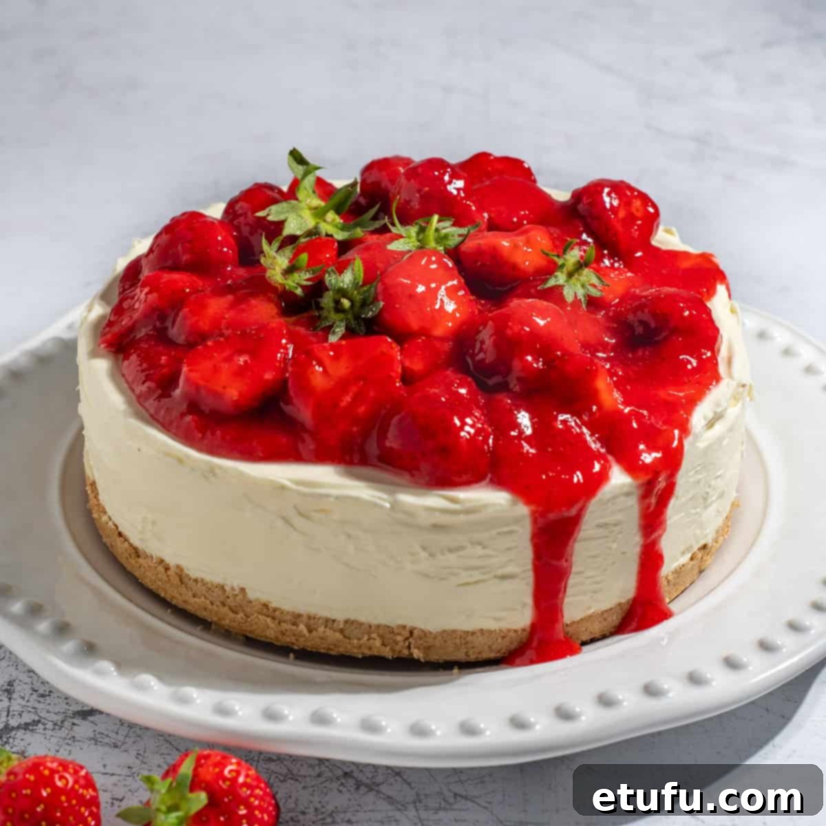 A finished strawberry and white chocolate cheesecake on a large white plate, beautifully garnished.