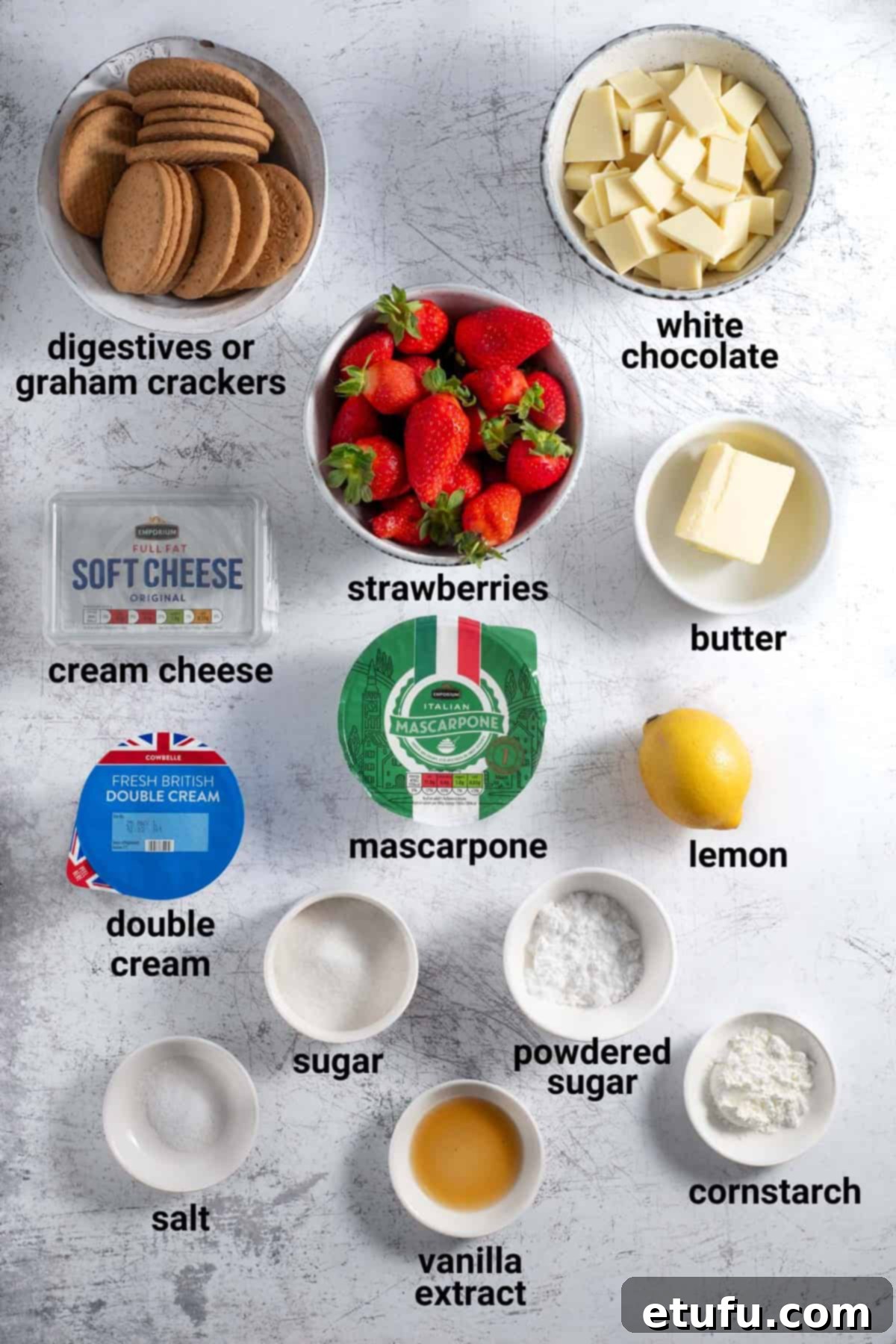 A flat lay of fresh strawberries, white chocolate, cream cheese, mascarpone, heavy cream, digestives, and butter for the cheesecake recipe.