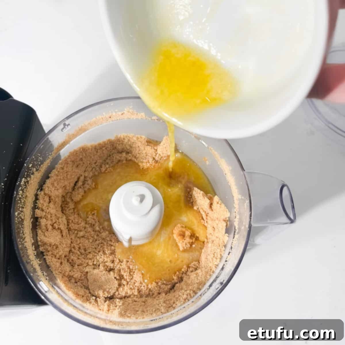 Adding melted butter to crushed cookie crumbs for the cheesecake crust.