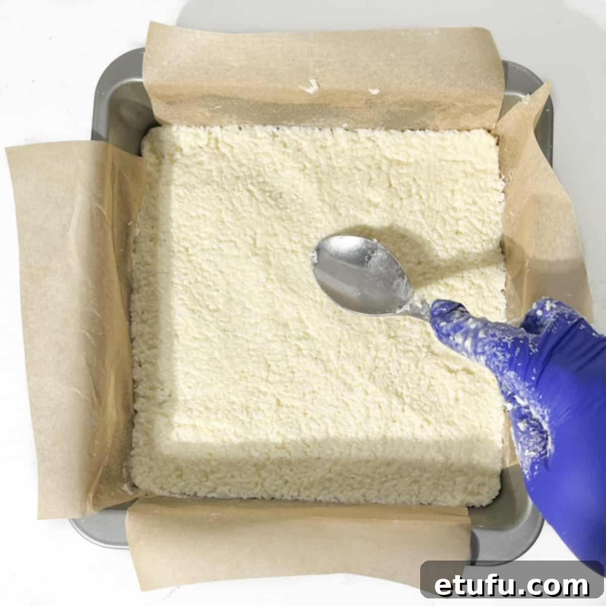 Flattening the white layer of the mixture in the tin.