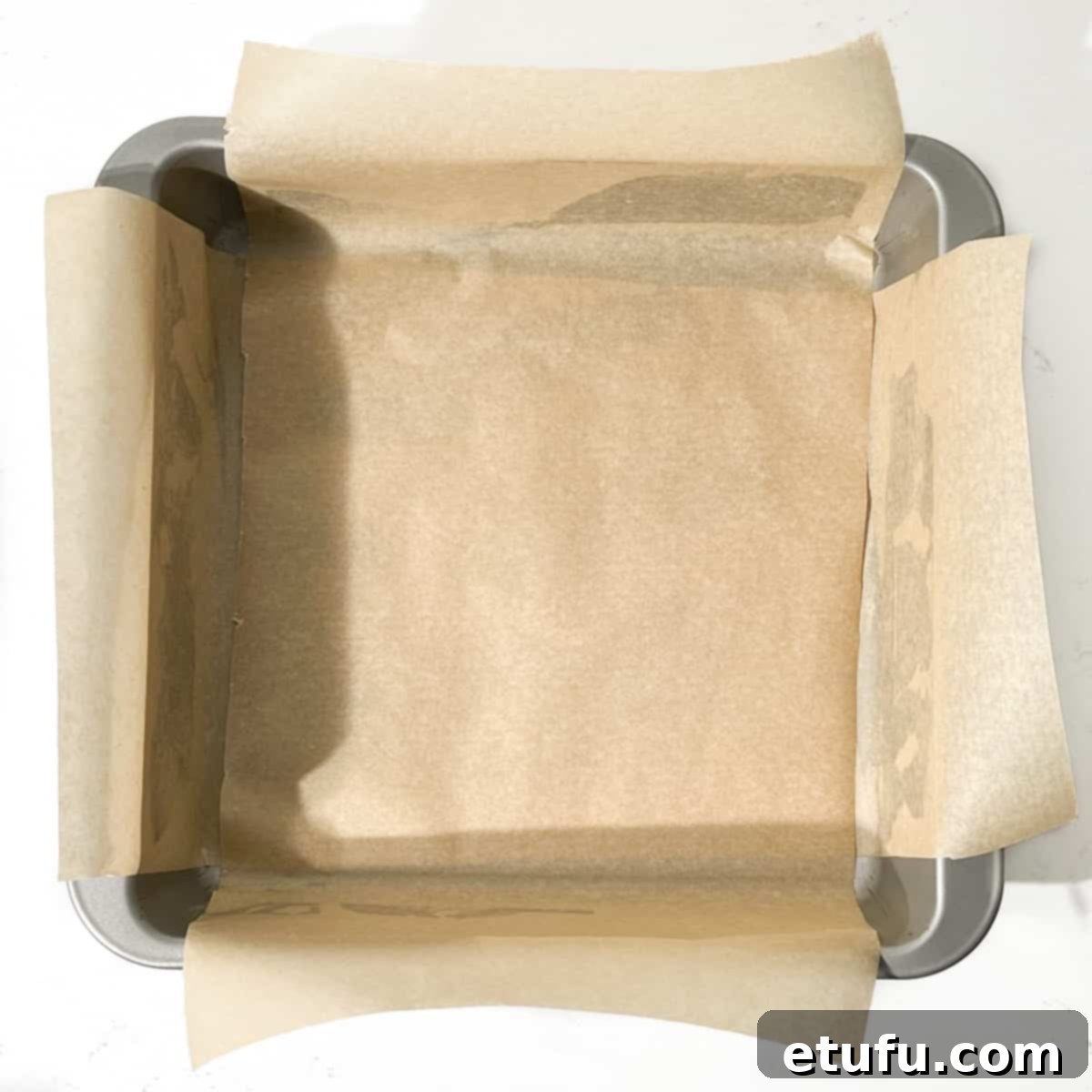 A square baking tin lined with baking paper.