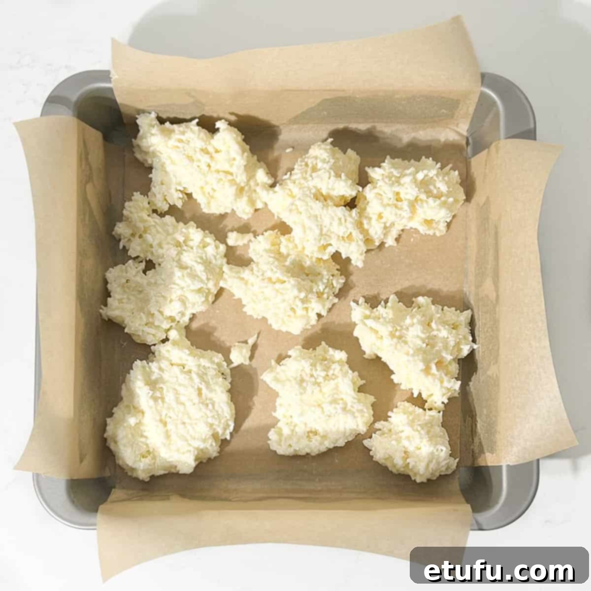 Dicing the white half of the coconut mixture into the tin.