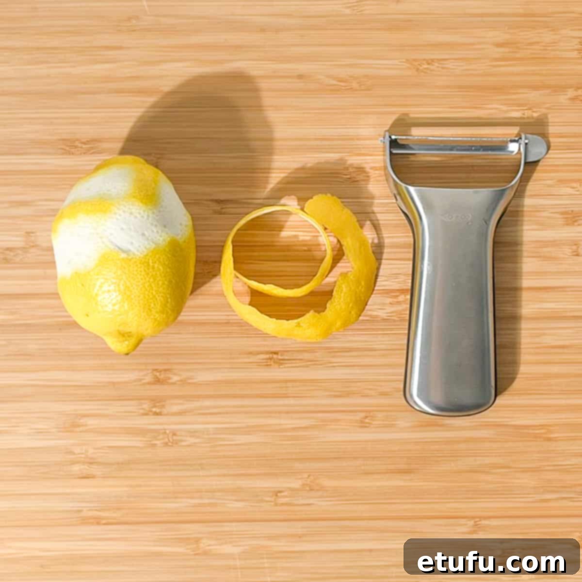 Peeling a long length of lemon peel with a peeler, preparing for the twisty.