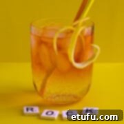 A medium glass of Rock shandy on a yellow background with an orange and yellow straw.