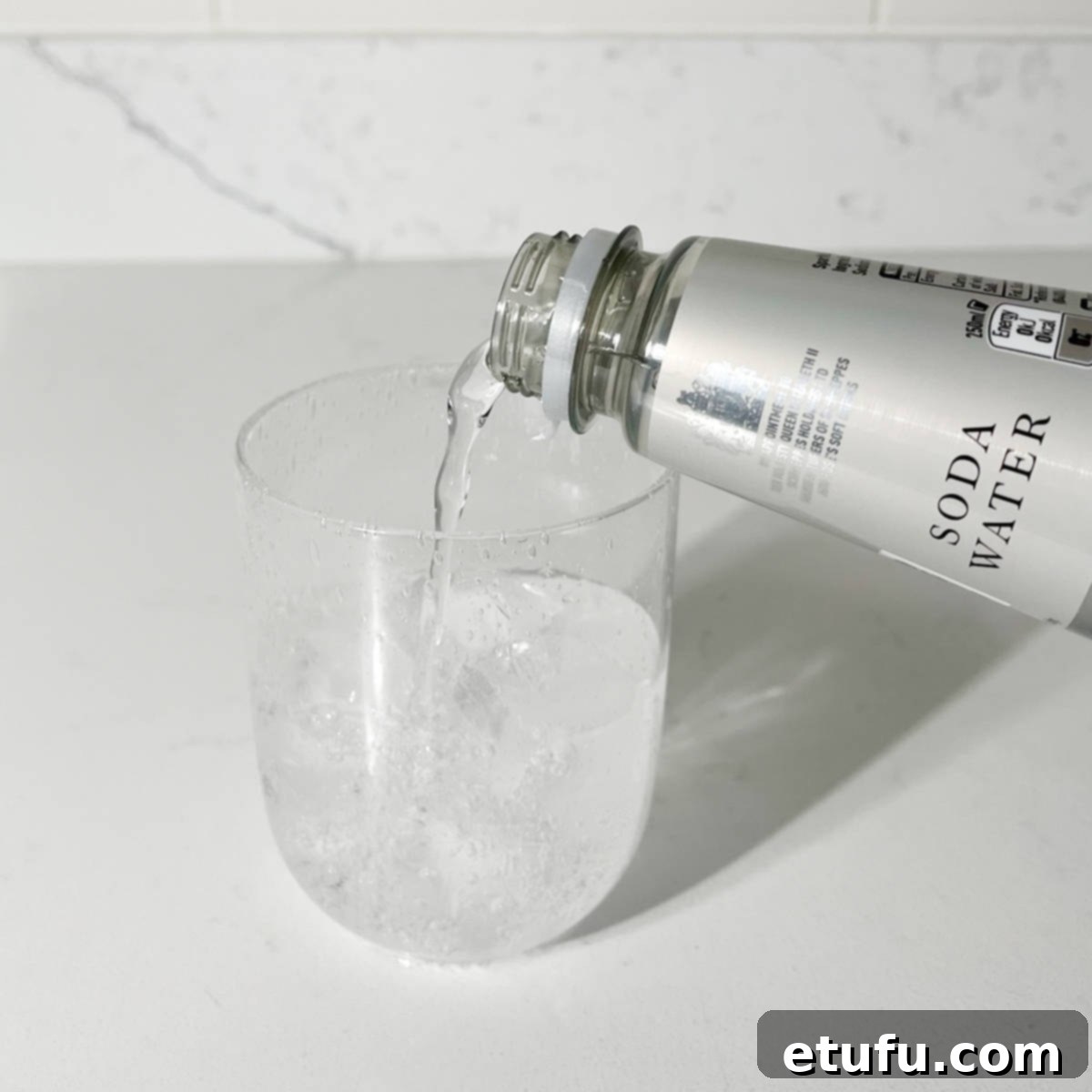 Adding soda water to the glass with ice.
