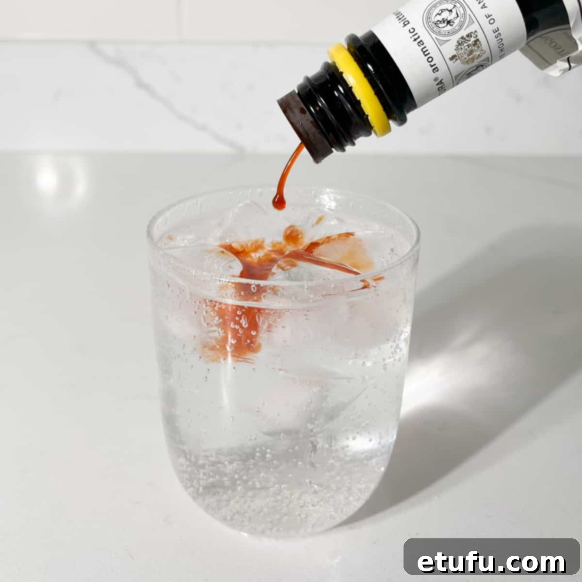 Adding Angostura bitters to the rock shandy, creating a beautiful color gradient.