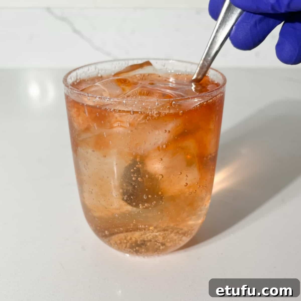 Giving the rock shandy a quick stir with a spoon to mix the bitters.