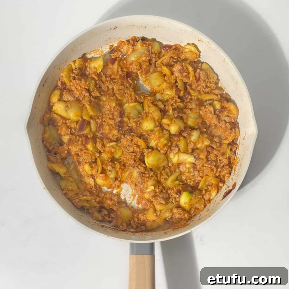 The sausage filling, incorporating diced courgette flesh, simmering in the pan, ensuring all flavors meld perfectly.