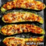 Stuffed courgettes on a baking tray with parmesan grated over.