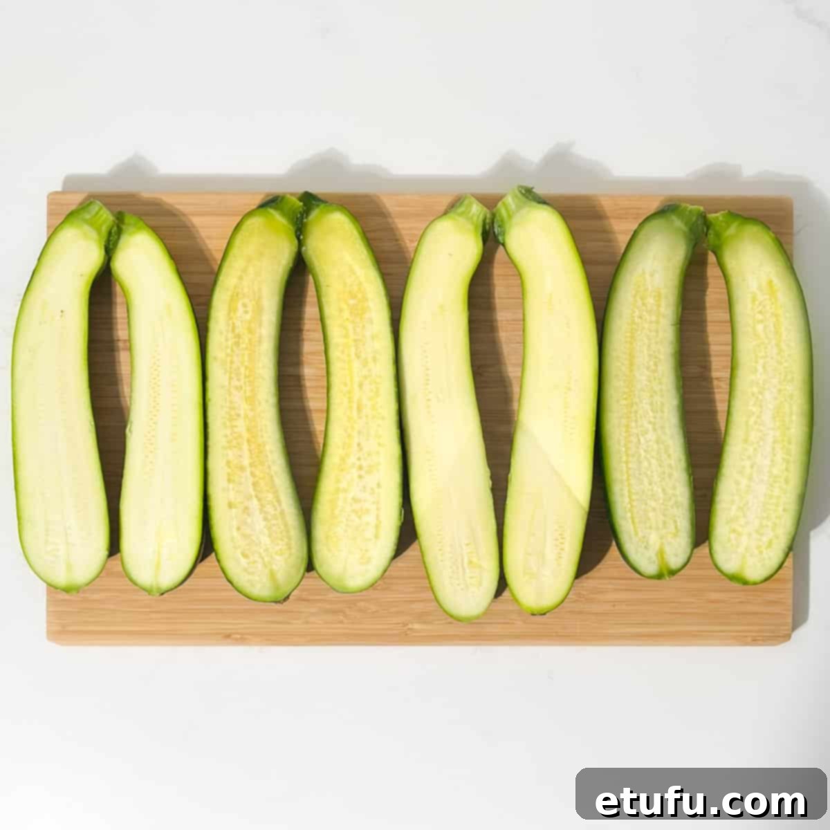 Freshly halved courgettes, neatly arranged on a cutting board, ready for scooping and stuffing.