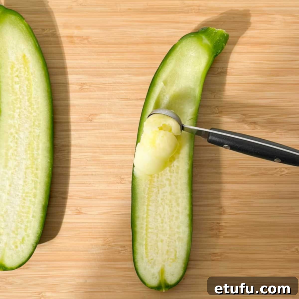 A melon baller scooping out the tender flesh from a halved courgette, creating a perfect cavity for the stuffing.