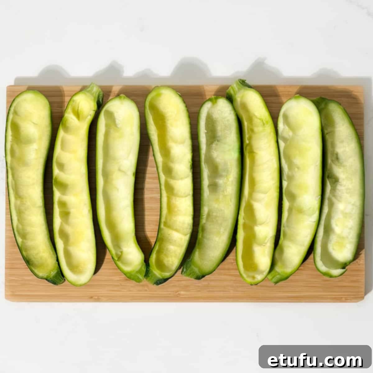Hollowed-out courgette halves, meticulously prepared and ready to be filled with the delicious sausage mixture.