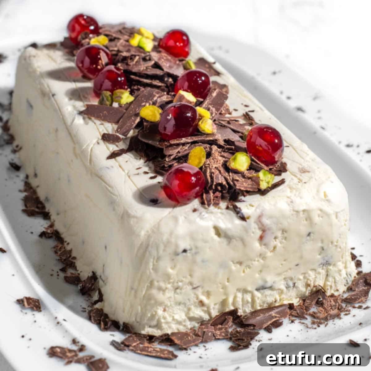 A stunning festive Cassata ice cream, lavishly decorated and ready to be sliced and served on a white serving plate, showcasing its colorful interior.