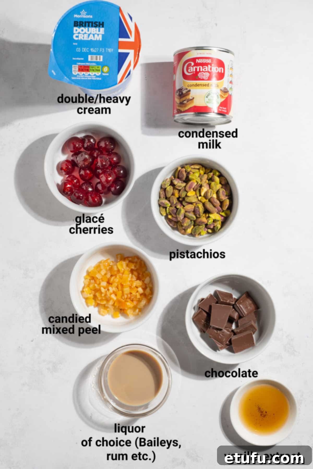 A vibrant selection of ingredients for homemade Cassata, including heavy cream, condensed milk, vanilla, various dried fruits, pistachios, and chocolate chunks, arranged appealingly on a clean surface.