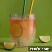 A glass of lemon, lime and bitters with two straws, on a green background.