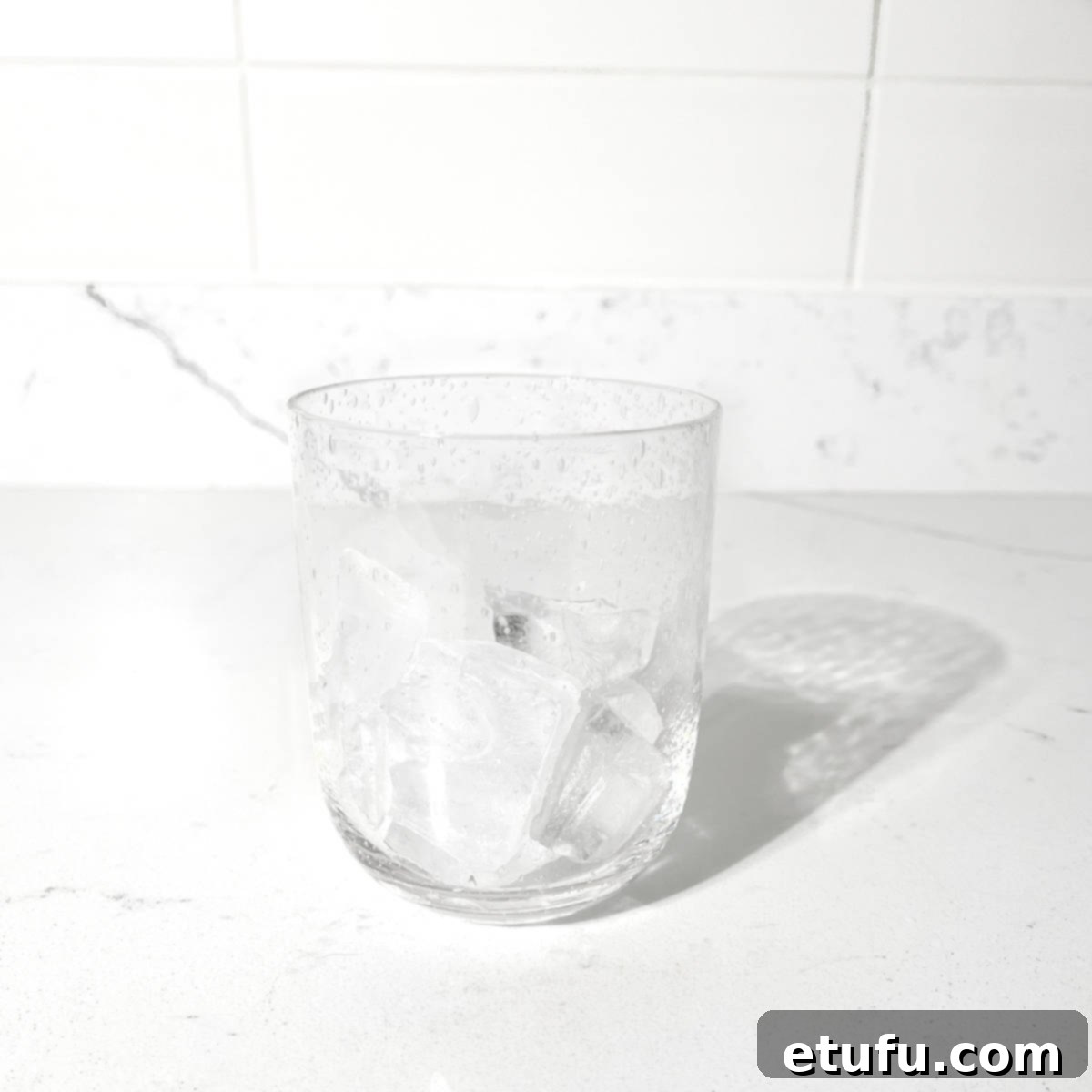 Adding ice to a glass for the lemon lime bitters.