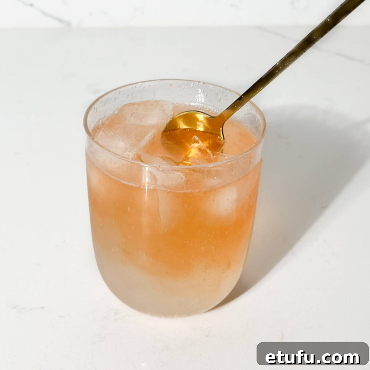 Stirring the lemon lime and bitters with a gold spoon.