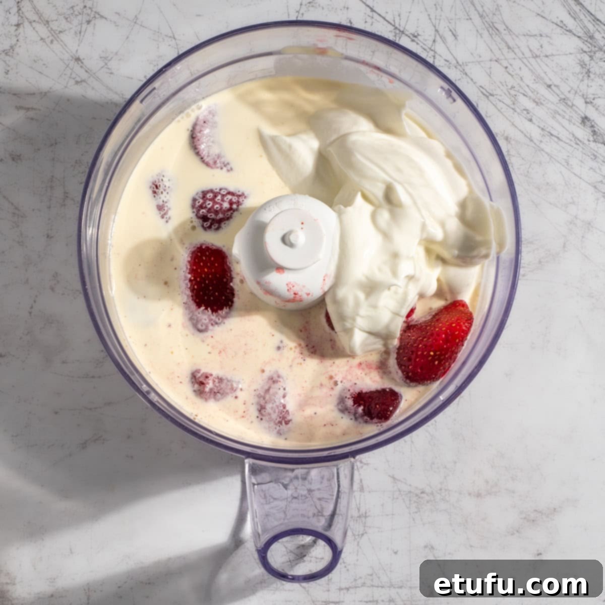 Creamy Strawberry Lassi 4 All ingredients for a strawberry lassi in a bowl of a food blender.