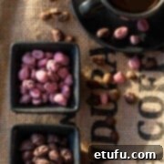 Ruby and dark chocolate covered coffee beans in black pots, on a coffee sack background.