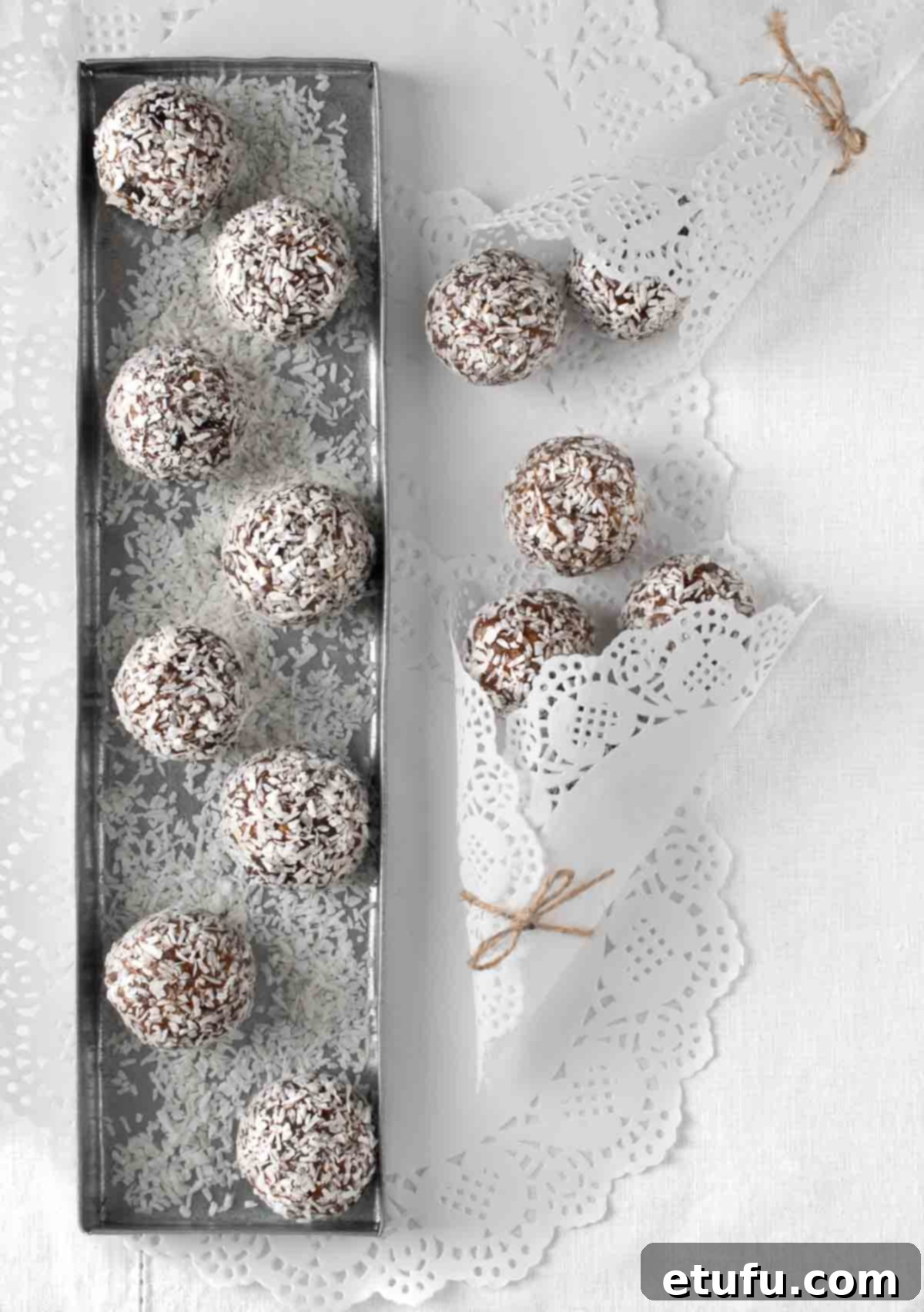 Exquisite date balls elegantly arranged on a gleaming silver tray atop a pristine white tablecloth, ready to be served.