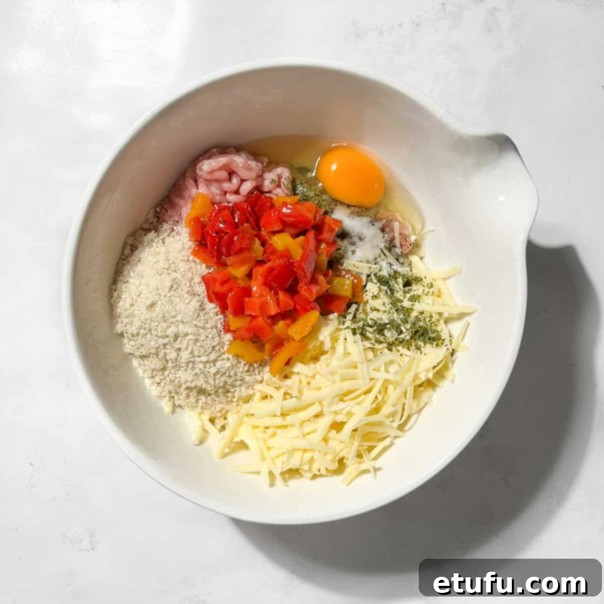 All the ingredients for chicken rissoles in a large white bowl.