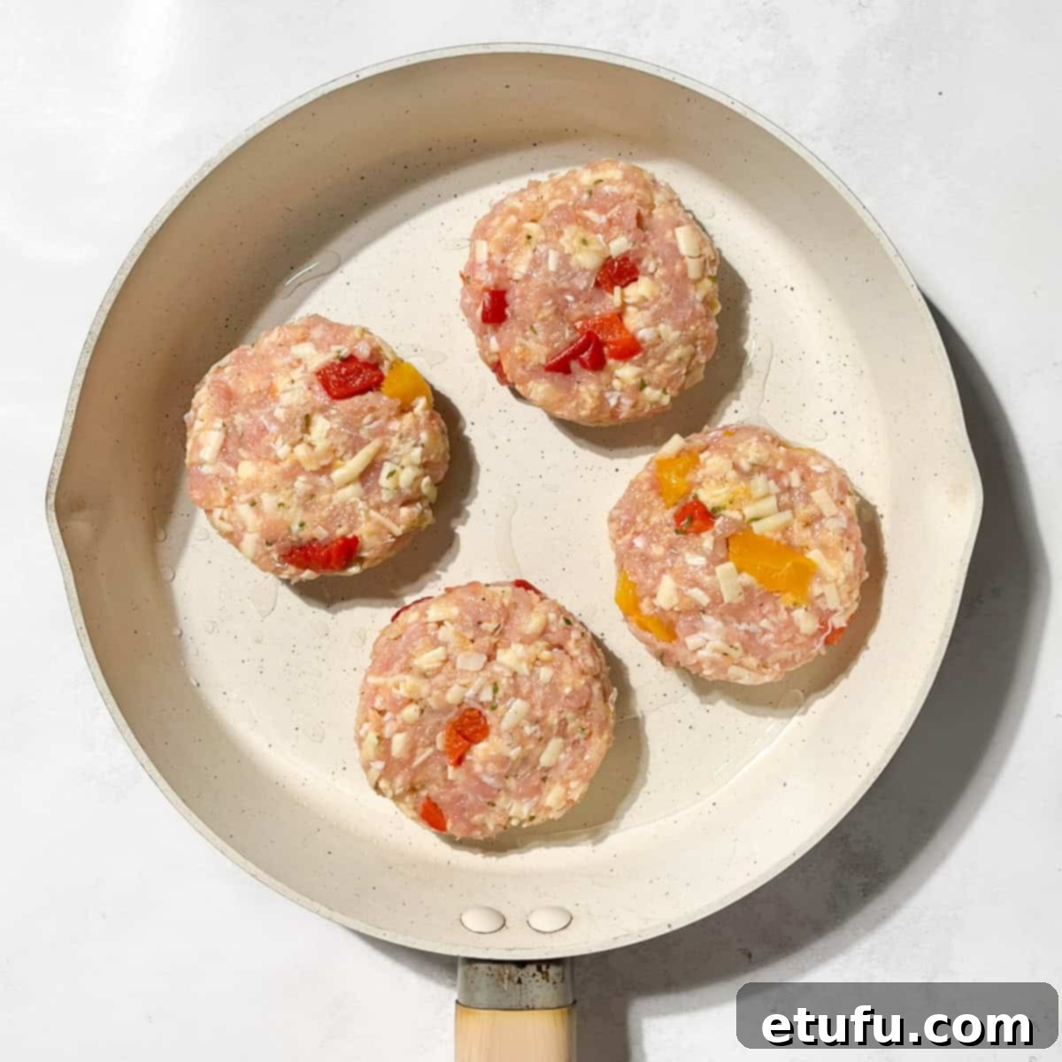 Rissoles frying in a large frying pan.