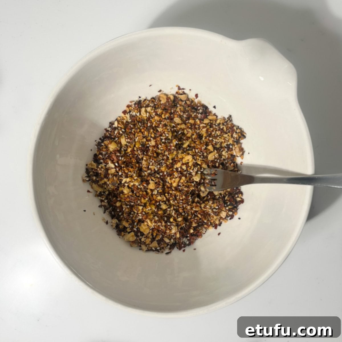 The crispy chilli oil dry ingredients are thoroughly mixed together in a large white bowl, forming a cohesive base.