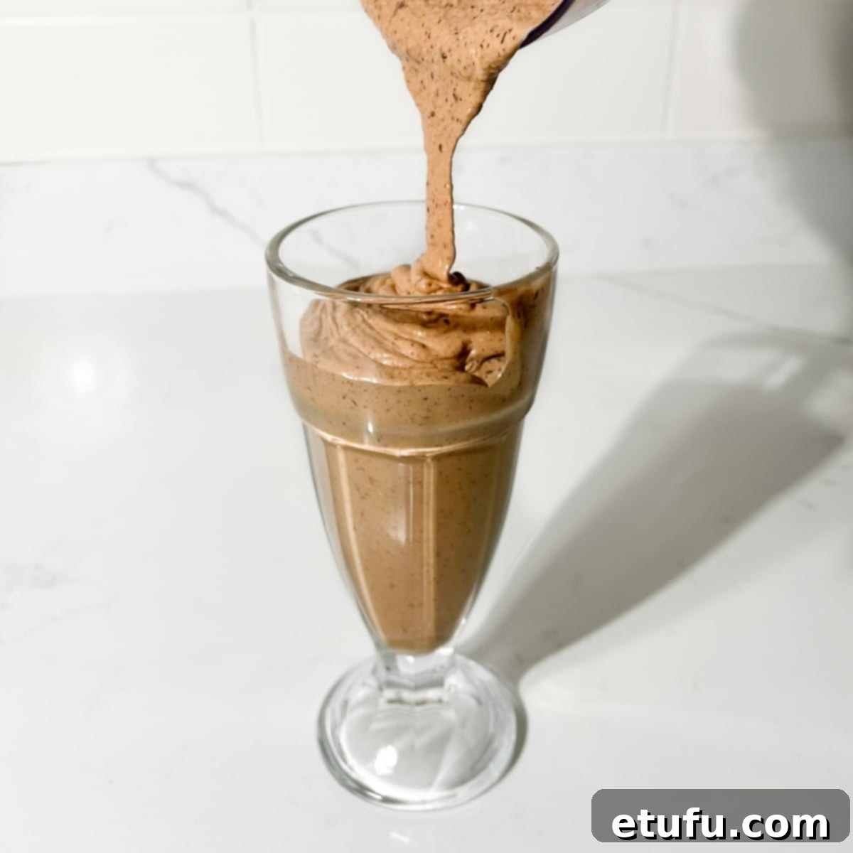 Nutella Milkshake Magic: Only 3 Ingredients 6 Pouring the Nutella milkshake into a milkshake glass.
