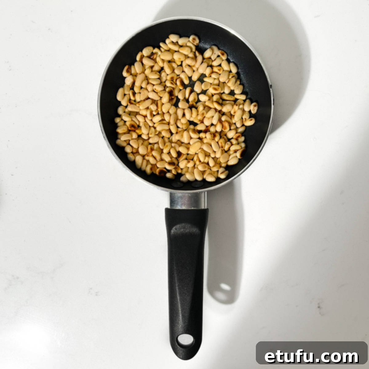Toasting pine nuts in a small pan.