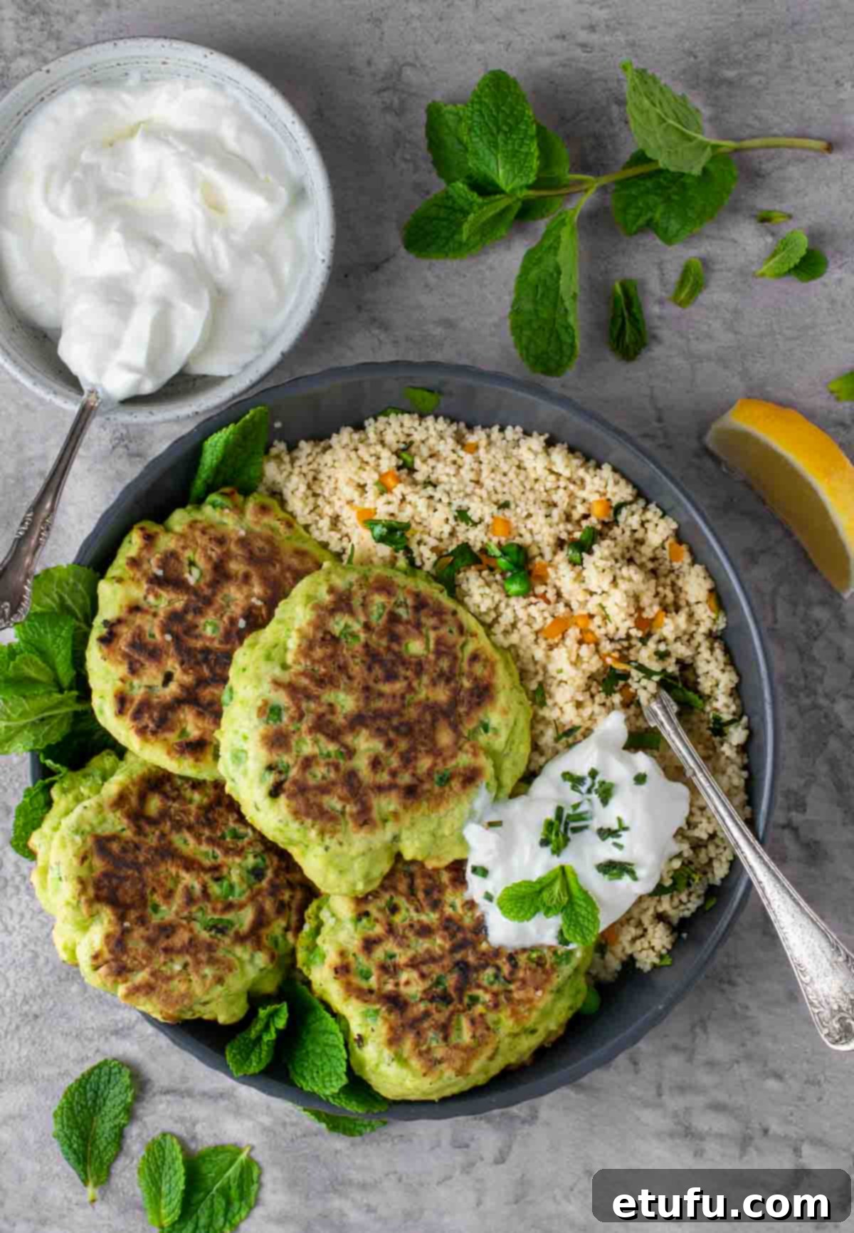 Four pea fritters in a bowl with a portion of couscous and a dollop of Greek yoghurt, ready to be served.